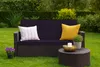 A dark purple outdoor sofa with two cushions and a small round coffee table in front of it, set on a green lawn with a hedge in the background. Voir les images du produit