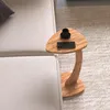 A small wooden side table with a phone and cup on it, next to a sofa. Náhled obrázku produktu