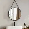 A round mirror with a black frame hangs above a white sink in a bathroom setting. Podgląd zdjęcia produktu