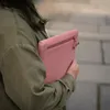 A person holding a pink sleeve. Voir les images du produit
