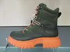 A single green boot with an orange sole is displayed on a shelf against a light gray and white background. Produktbild-Vorschau