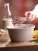 A hand is using a whisk to mix ingredients in a bowl, with a bottle of milk and eggs in the background. Anteprima dell’immagine prodotto