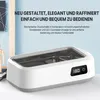 A white ultrasonic cleaning device with a digital display is shown on a light blue and white background. Text overlays describe its features. Produktbild-Vorschau
