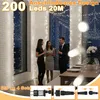 People are standing in a room decorated with string lights, with a table set for a meal in the background. Náhľad obrázku produktu