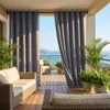 A balcony with outdoor furniture and curtains overlooking the ocean. Náhľad obrázku produktu