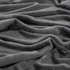 A close-up view of a soft, textured gray blanket with folds and creases. Produktbild-Vorschau