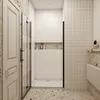 A modern bathroom with a glass shower enclosure, white tiled walls, and terrazzo flooring. Produktbild-Vorschau