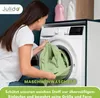 A woman is putting a green sheet into a washing machine. Produktbild-Vorschau