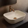 A close-up shot of a beige basin with a gold faucet and drain. Anteprima dell’immagine prodotto
