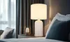A bedside table with a lamp and a small vase. Anteprima dell’immagine prodotto