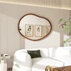A modern living room with a white sofa, a unique mirror, and framed botanical prints. Produktbild-Vorschau