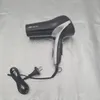 A black and silver hair dryer with its cord and plug is placed on a textured light gray surface. Produktbild-Vorschau