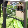 A person is standing next to a multi-tiered serving cart outdoors, with bottles and vegetables on it. Produktbild-Vorschau