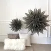 Two paper star decorations hanging on a wall above a sofa with cushions. Produktbild-Vorschau