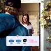 A delivery person hands a package to a woman at her doorstep. Produktbild-Vorschau