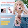 A young girl holds a pink digital camera to her face, and another shot shows the camera being placed into a jeans pocket. Produktbild-Vorschau