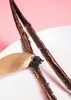 A close-up shot of two vanilla beans being scraped with a knife on a white plate, with a pink background. Produktbild-Vorschau