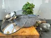 A speckled gray pot with a glass lid sits on a wooden board, next to a small plant and jars of spices. The background is a kitchen setting. Produktbild-Vorschau