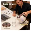 A man is pouring water from an electric kettle into a glass on a desk with a laptop and notebooks. Podgląd zdjęcia produktu