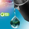 Water pouring from a kettle into a water drop containing a mountain landscape. Voir les images du produit