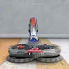 A vacuum cleaner attachment with rotating brushes is shown on a floor that transitions from wood to tile. Produktbild-Vorschau