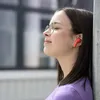 A young woman wearing glasses and red earbuds leans against a pole, eyes closed, enjoying music. Anteprima dell’immagine prodotto