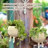 Two hanging planters with smiling faces and legs, filled with plants, are displayed against a wooden background. Anteprima dell’immagine prodotto