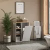 A laundry room scene featuring a white and wood-tone cabinet with open shelves and a laundry basket, a plant, a towel rack with towels, and a rug. Náhled obrázku produktu