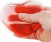 A hand holding a red heart-shaped hand warmer. Náhľad obrázku produktu