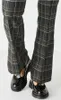 A close-up view of a person's legs wearing plaid pants and black shoes. Produktbild-Vorschau
