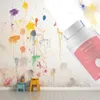 Rosa Small Roller-Multi Color Mini Paint Behälter mit weißem Roller, vor einer Wand mit bunten Farbspritzern Anteprima dell’immagine prodotto