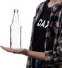 A person is holding a clear glass bottle on their palm. Produktbild-Vorschau