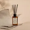 A reed diffuser with wood sage scent is placed on a textured surface with soft lighting. Náhľad obrázku produktu