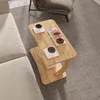 A C-shaped side table with two cups of coffee and donuts on it, placed next to a sofa and a chair on a patterned rug. Náhled obrázku produktu