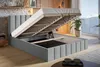 A bed with its storage compartment open, showcasing the slatted base and storage space. The room has a modern, cozy feel with wooden accents and a view of mountains outside. Náhled obrázku produktu
