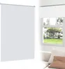 A white roller blind is shown in a split image. On the left, a large portion of the blind is visible against a white background. On the right, the blind is shown installed above a window, with a view of a house and garden outside. Produktbild-Vorschau