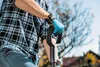 A person wearing a plaid shirt and blue gloves is holding the handle of a shovel. Produktbild-Vorschau