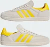 A pair of Adidas Humanrace Samba sneakers in white and yellow. Produktbild-Vorschau