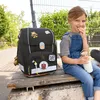 A young girl sits on a wooden bench outdoors, holding a water bottle and eating a snack, with a backpack next to her. Anteprima dell’immagine prodotto