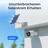 A security camera and its solar panel are mounted on a white wall, with a blue sky in the background. Produktbild-Vorschau