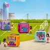 Four LEGO Friends play cubes are displayed on a soccer field with a cityscape and bridge in the background. Produktbild-Vorschau