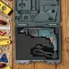 A drill and various tools laid out on a wooden surface, with the drill inside its case. Produktbild-Vorschau
