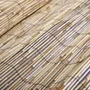 A close-up, diagonal view of a reed fence made of natural reeds bound together with black string. Náhled obrázku produktu