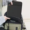 A person is putting a black laptop sleeve into a backpack. Produktbild-Vorschau