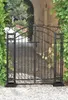 A black wrought iron gate in a garden setting, with ivy growing on either side. Podgląd zdjęcia produktu