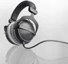 A pair of black over-ear headphones with a coiled cable, shown on a reflective surface against a white background. Produktbild-Vorschau