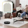 A couple relaxing on a couch in a living room, with a robot vacuum on the floor and a coffee table in the foreground. A stack of cleaning cloths is shown in a graphic overlay. Produktbild-Vorschau