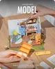 A miniature house model being assembled, with hands holding tweezers and parts of the model. Podgląd zdjęcia produktu