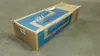 A cardboard box with blue markings on a concrete floor. Voir les images du produit