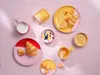 A breakfast spread with croissants, yogurt, fruit, and drinks arranged on a pink tablecloth. Produktbild-Vorschau
